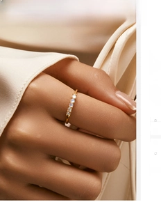 Close-up of a slim gold s925 silver ring featuring five moonstones on a female finger