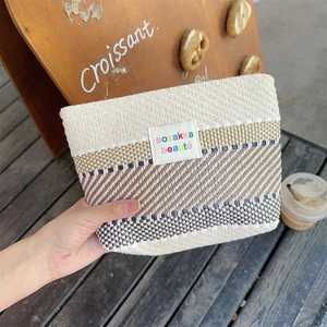 Macro shot of striped woven toiletry bag with sozakka beauté label and secure zipper