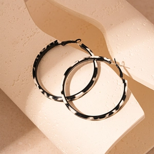Minimalist black and white zebra pattern hoop earrings on a stone background