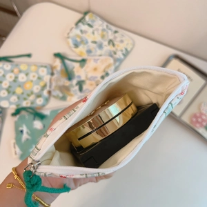 Close-up of hand holding a floral cotton mini pouch with cosmetics inside for storage