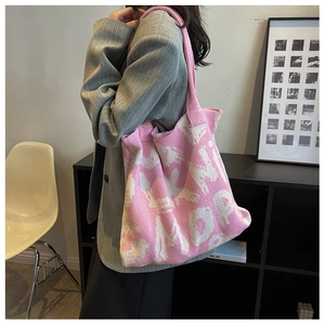 Detailed side view of a pink and white knit tote bag with jacquard letter patterns