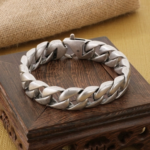 Detailed macro view of vintage silver Cuban link chain with aged metal texture on wood