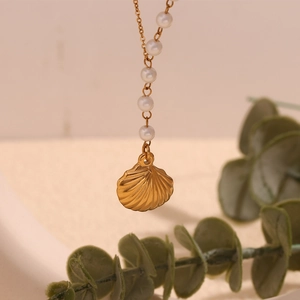 Macro view of 18K gold shell pendant and white pearls on a minimalist necklace