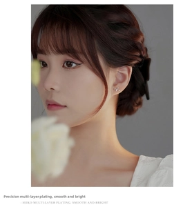Close-up of elegant silver bow stud earring worn by model with minimalist floral background