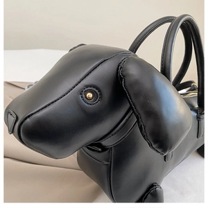 Detail shot of the dachshund-shaped handbag showing matte black leather and gold hardware