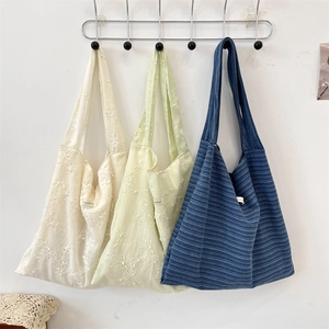 Detail of canvas tote bags with floral embroidery and wide straps hanging on hooks