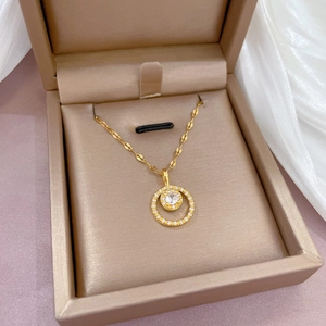 Detail of round gold necklace with micro-paved zircons in a champagne jewelry box