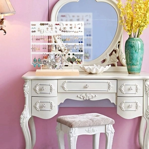 Detail view of multi-tier white earring display rack with a natural wooden base on vanity