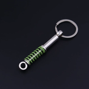 Detail of silver metal car shock absorber keychain with green spring on dark background