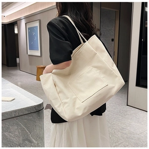 Detailed back view of a minimalist cream canvas tote bag with functional outer pocket