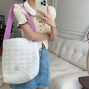 Detail of white heart-quilted shoulder bag with purple strap and SOZAKKA brand patch