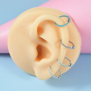 Close-up of four stainless steel BCR septum rings with iridescent opal beads on ear model