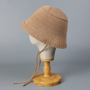 Close-up of camel knit bucket hat with delicate tie straps on a fabric display mannequin