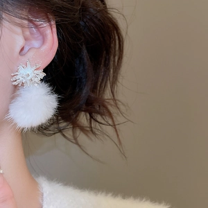 Close-up of elegant silver snowflake stud earrings with white faux fur pompom on model