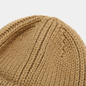 Macro detail of khaki chunky knit beanie showing thick stitch texture and winter warmth