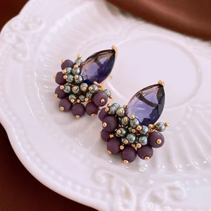 Luxury vintage gold drop earrings with purple teardrop crystal and pearls on a white tray