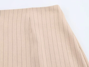 Gros plan détaillé de la taille d'une jupe à fines rayures beige clair avec pinces
