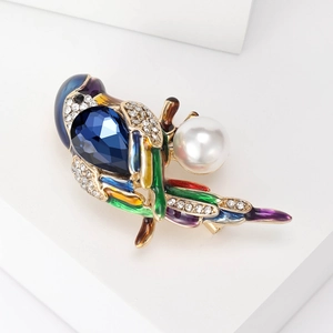 Detailed view of enamel bird brooch with blue crystal, rhinestones, and white pearl