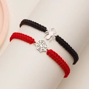 Detailed view of handmade woven bracelets with silver spider and cobweb charms in black and red