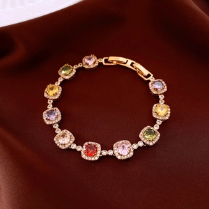 Macro view of 18k gold plated bracelet with colorful cubic zirconia on red silk