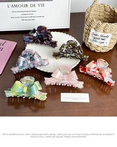 Detailed view of large acetate bow hair claws in six artistic patterns and marble textures