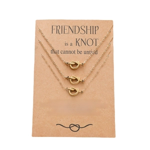 Three-piece gold knot necklace set on a brown kraft card for friendship gifts