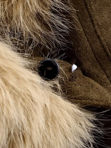 Détail d'une veste d'hiver vert olive avec col en fourrure marron et boutons noirs
