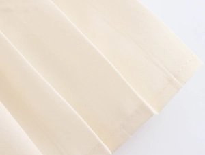 Détail de robe élégante en tweed montrant la texture plissée et les finitions de couture