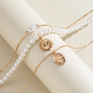 Detailed close-up of layered beaded necklace with eye and snake charms in gold finish