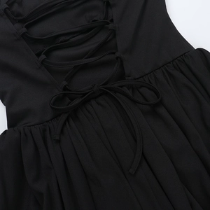 Close-up of the black backless dress featuring cross-strap ties and waist pleat details