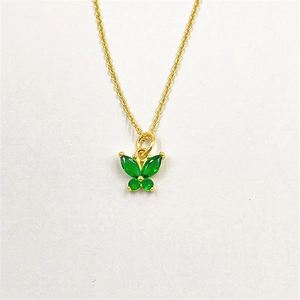 Détail du pendentif papillon doré avec des pierres de zircon vert serties avec soin