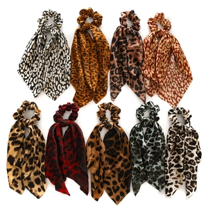 Flat lay of nine satin leopard print scrunchies with long ribbons in diverse colors