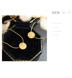 Detail of sliding Fu and Xi character pendants on gold plated stainless steel snake chains