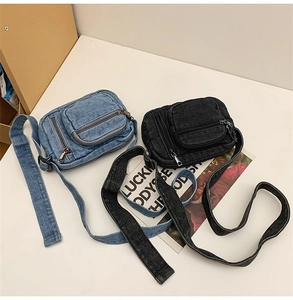 Top view of blue and black denim crossbody bags featuring front zippers and wide straps