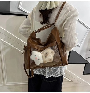 Close-up of vintage brown leather ita bag with transparent window and plush charms