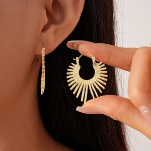 Detailed view of gold sunburst drop earrings with irregular metallic texture on model