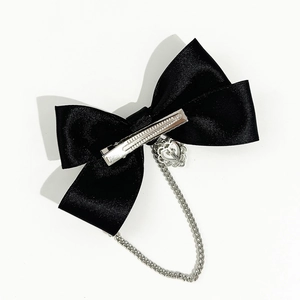Detail of black satin bow hair clip with silver chain and heart cross pendant
