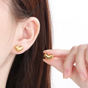 Gros plan détaillé des boucles d'oreilles cœur plaquées or 18 carats portées par un mannequin