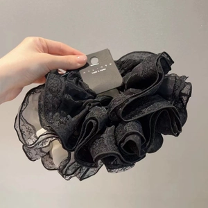 Gros plan détaillé d'un grand chouchou en dentelle noire avec texture ondulée et étiquette