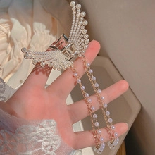 Close-up of golden metal butterfly hair claw clip with white pearls and long tassels