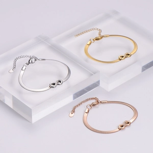 Three infinity charms bracelets in gold silver and rose gold on acrylic blocks