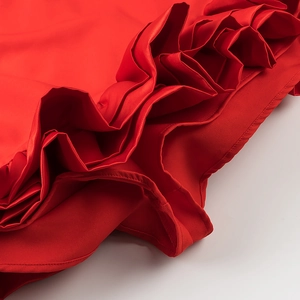 Detail of red ruffle dress showing smooth satin fabric texture and premium hem stitching