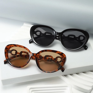 Fashion cat eye sunglasses with gold chain temples on geometric props in black and tortoiseshell