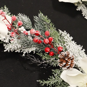 Guirlande de Noël avec magnolias blancs, baies rouges, pommes de pin et neige artificielle