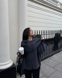 Detail of dark grey loose wool cape coat with scarf on model in London street style