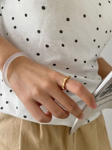 Detailed view of a gold-plated geometric link ring styled with a trendy polka dot shirt
