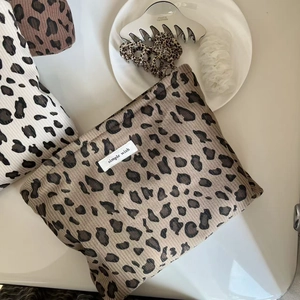 Vue à plat de la trousse de maquillage en velours côtelé léopard avec étiquette simple