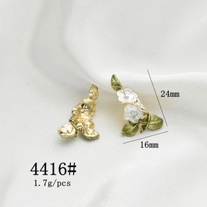 Detail view of 24mm x 16mm gold rose earrings with white enamel on silk background