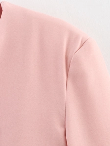 Vista macro del blazer rosa che mostra la trama del tessuto twill e le cuciture di qualità