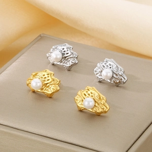Close-up of gold and silver irregular textured earrings with pearls on silk